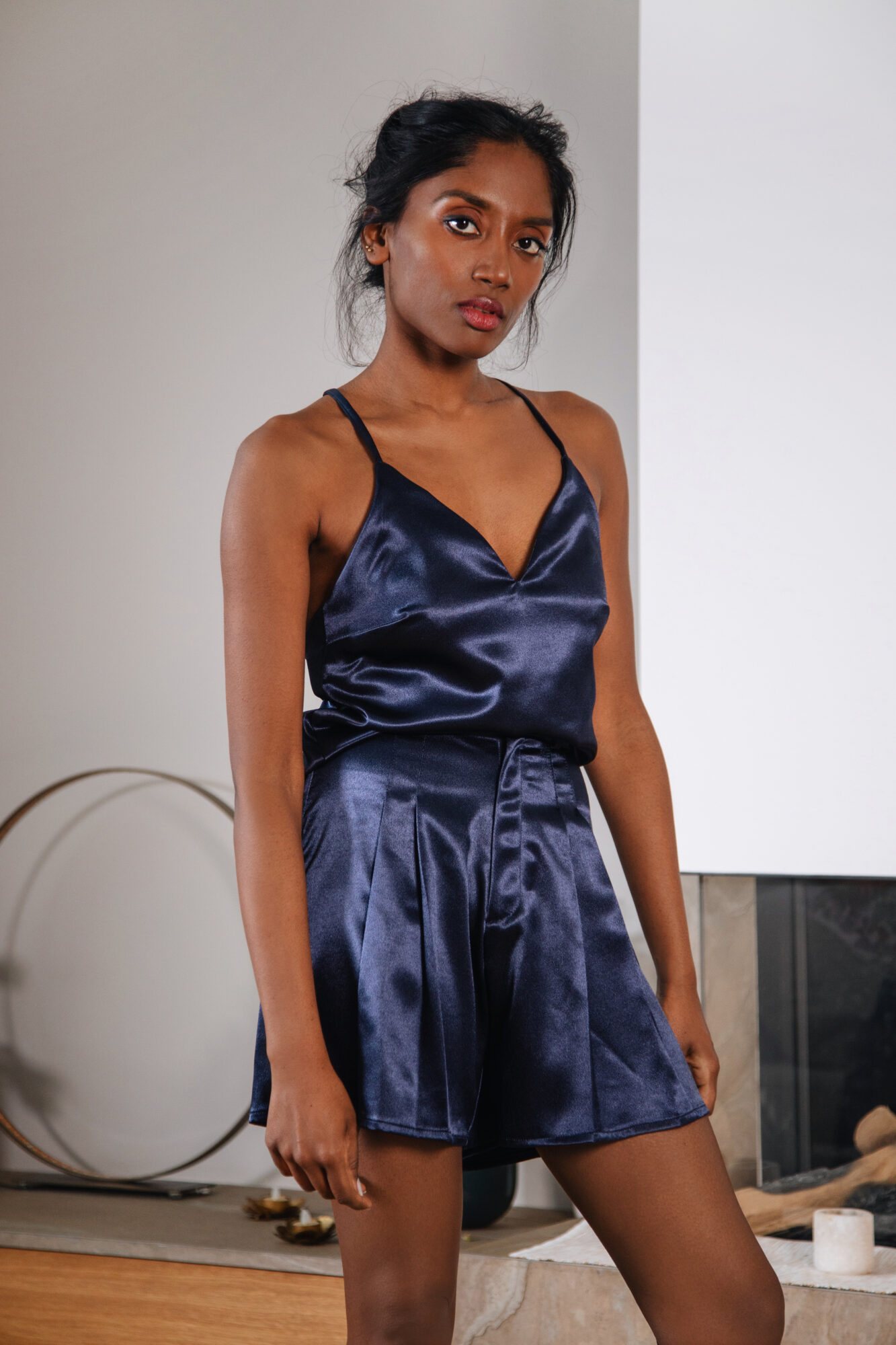 Le modèle porte le top Tess fluide en satin bleu nuit avec des bretelles ajustables