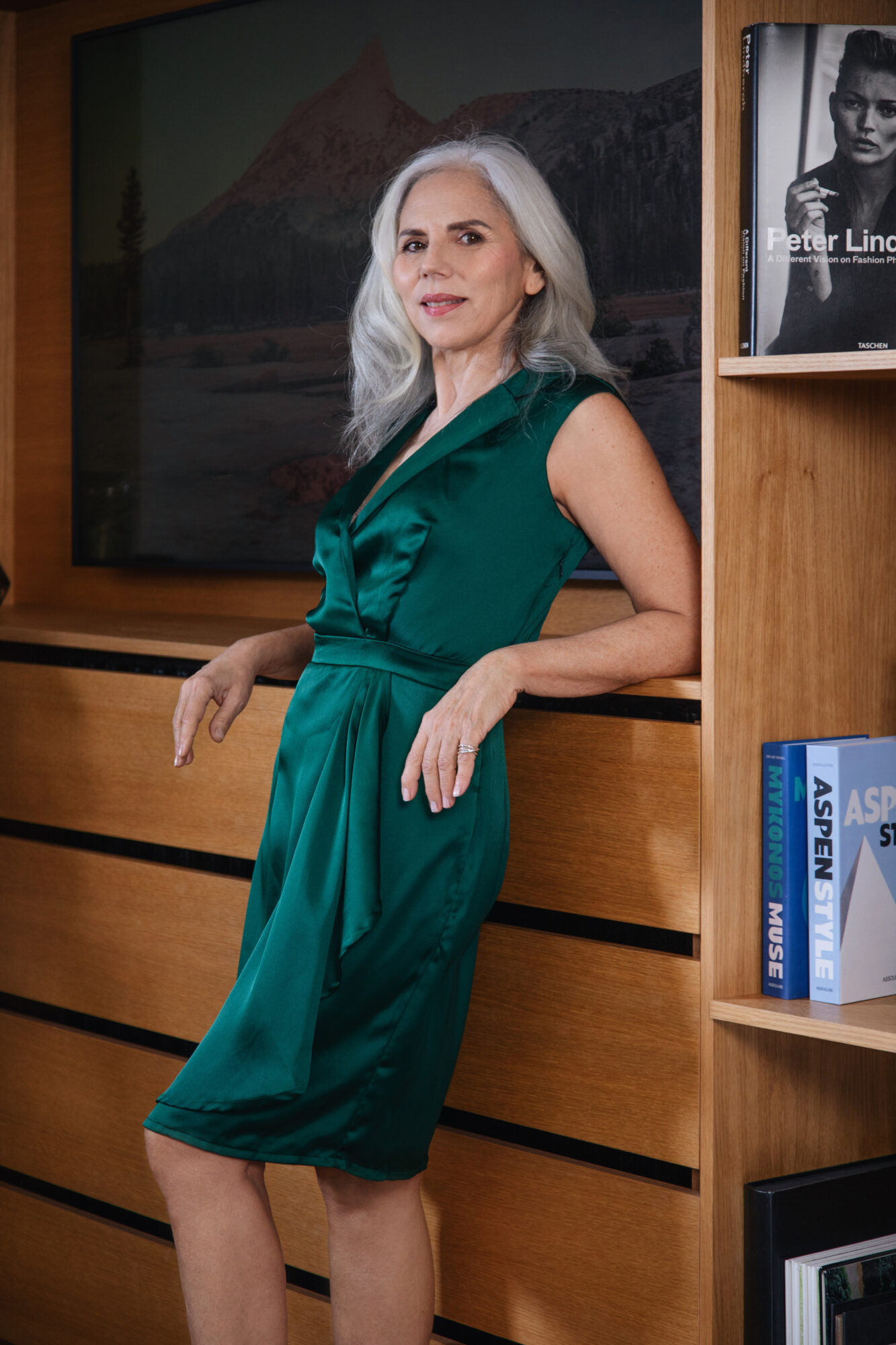 Une femme porte une robe courte sans manches avec bas drapé, en satin vert, de la collection de vêtements sur-mesure Therese